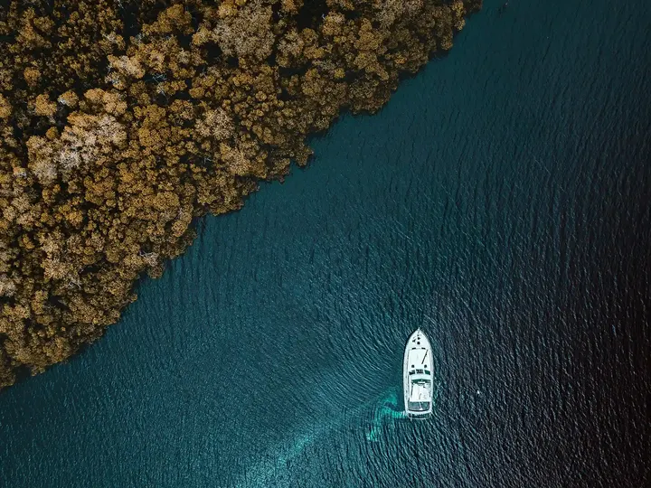 Boat on turquoise water beside a rocky shore