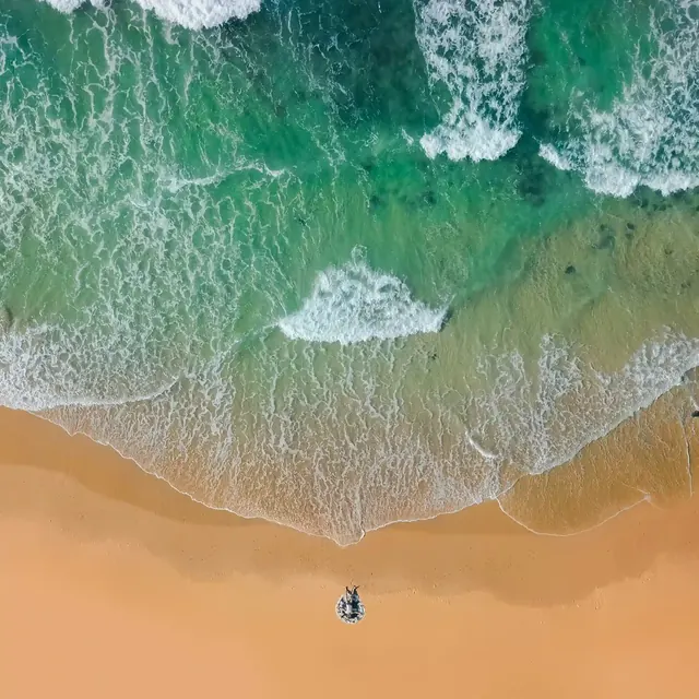 Waves breaking on a sandy beach, seen from above