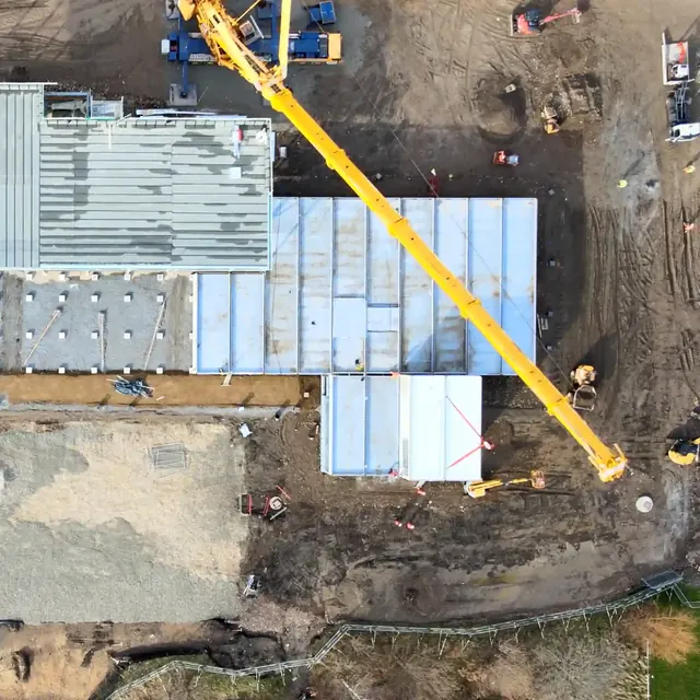 Crane lifting a module into place on a construction site