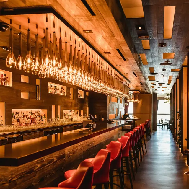 Long cocktail bar lit with warm pendant lights