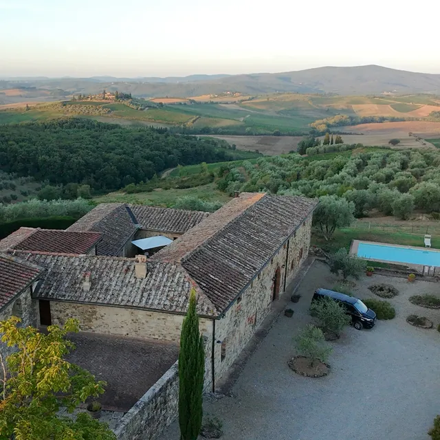 Aerial view of a Tuscan stone villa with a swimming pool and olive trees