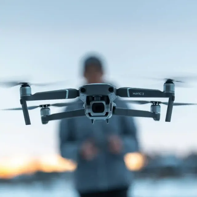 Camera drone hovering in front of its pilot