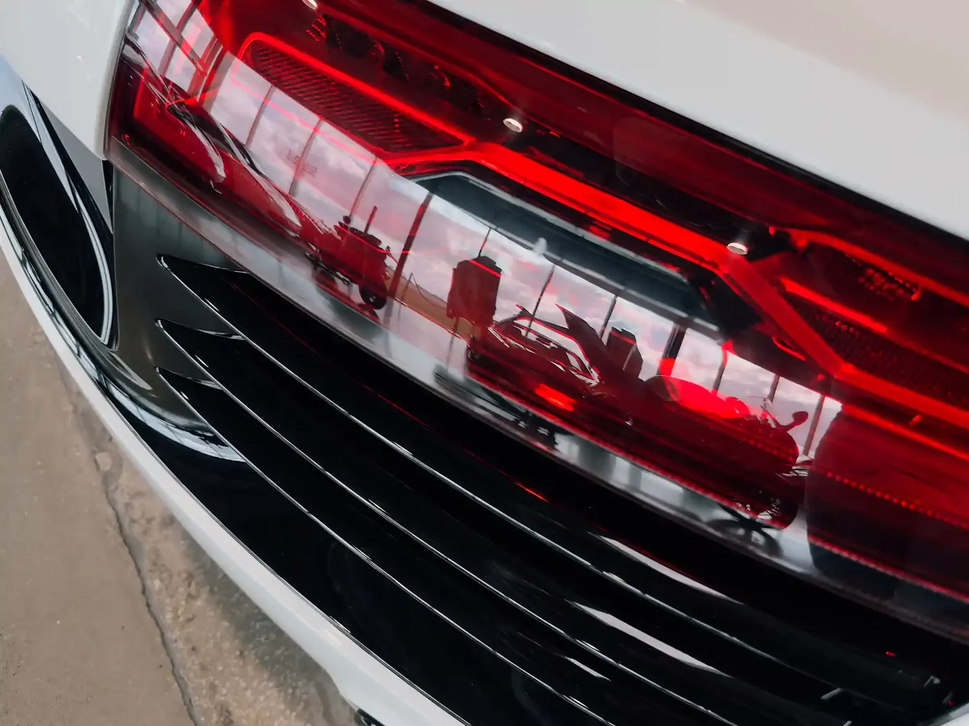 Close-up of a red supercar tail light reflecting the showroom