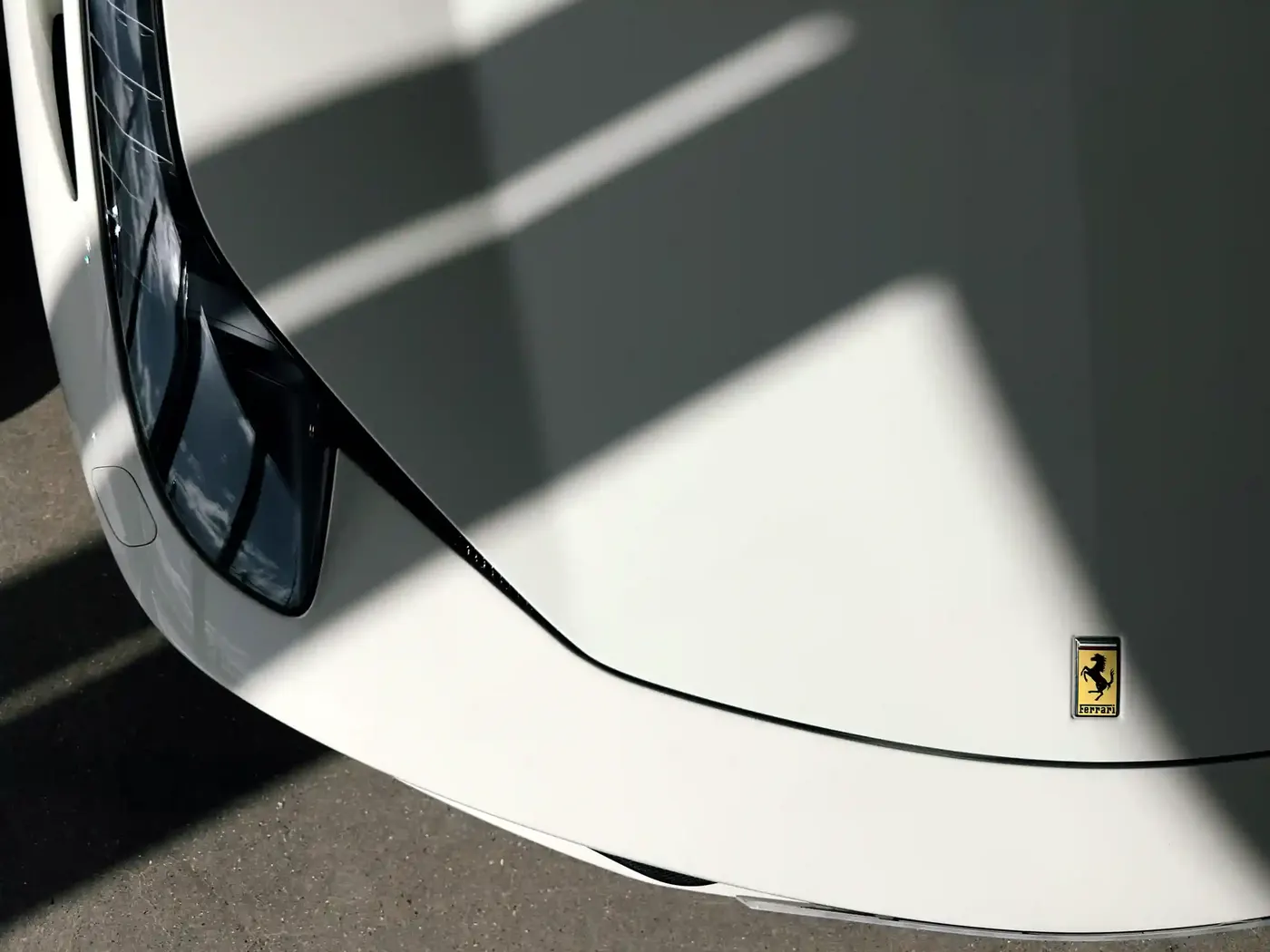 Low-angle detail of a white Ferrari bonnet and badge