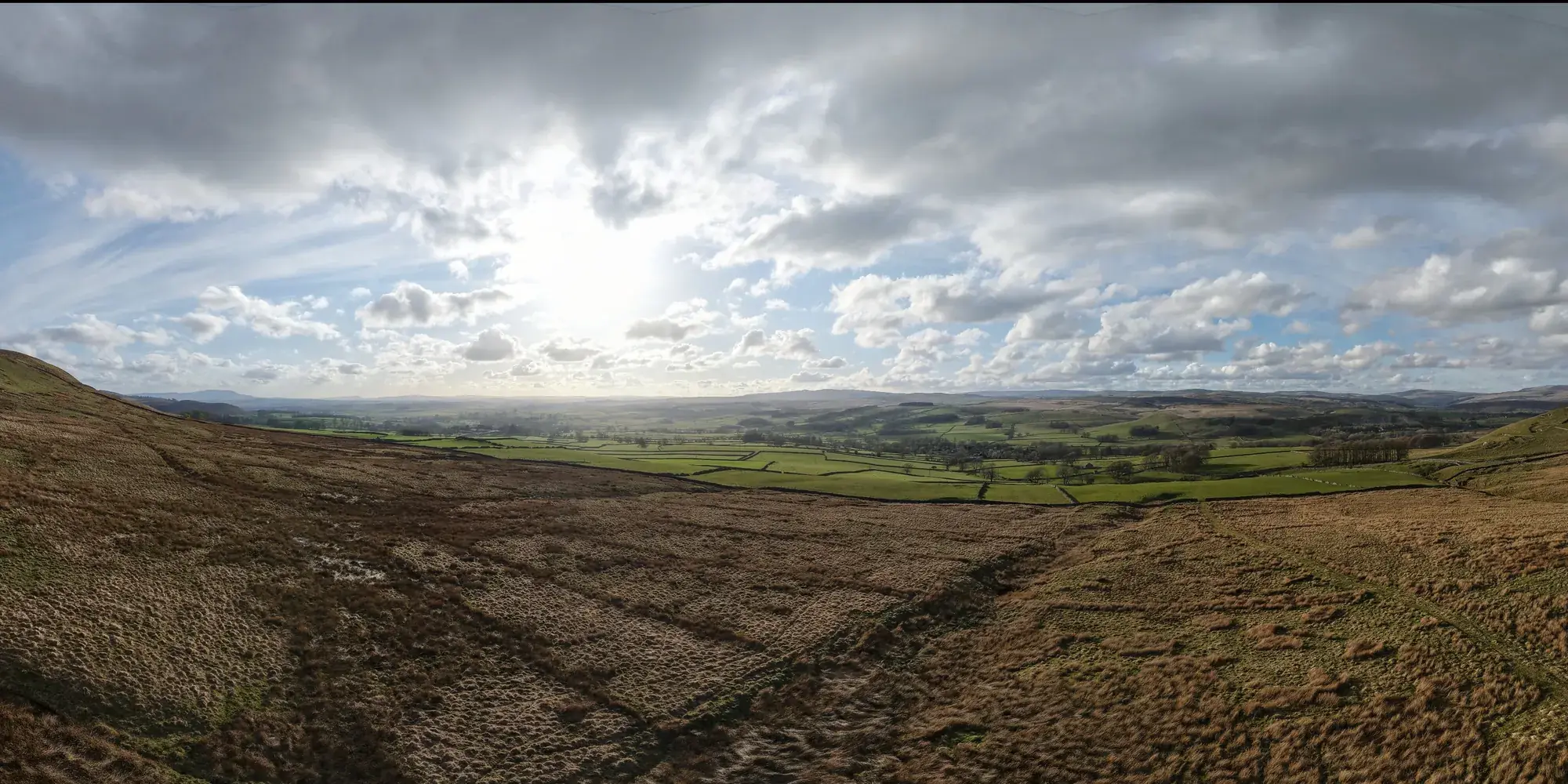 Aerial panorama over moorland and a green Dales valley from The Cross